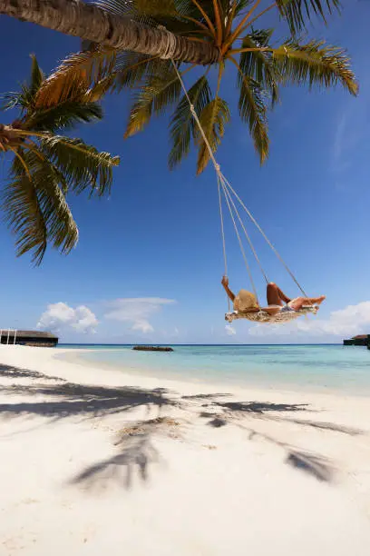 Photo of Carefree woman relaxing in a swing on the beach.