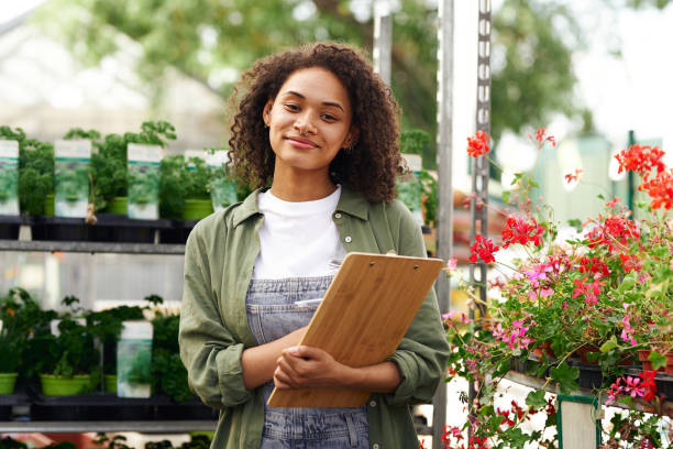 istock Smiling woman gardener making notes in clipboard while standing in garden center 1733238985