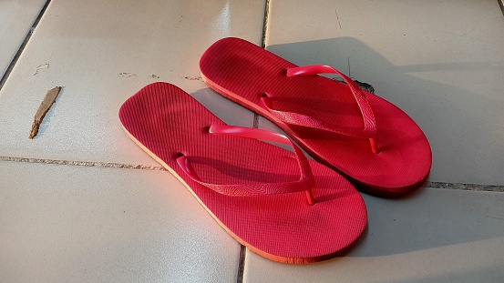 Red flipflop slipper with shadow of evening sunset