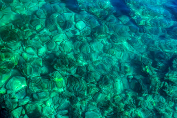 Pebbles shining under beautiful clear turquoise water, background or texture.