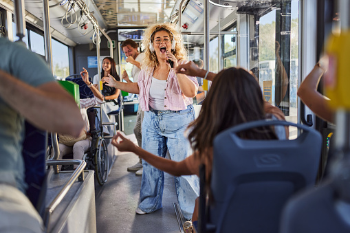 Carefree overweight woman having fun while listening music and singing during a party in public transport.