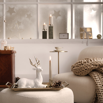 Cozy and stylish christmas living room interior with design armchair, retro shelf, poufm big window, christmas wreath, deer, gifts, decoration and accessories. Santa claus is coming. Template.
