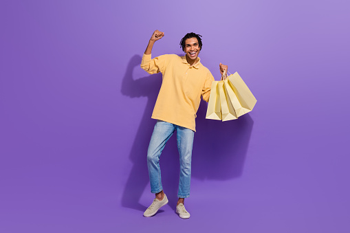Full size body cadre of shopaholic youth guy fist up hooray open brand store adidas new collection sale isolated on violet color background
