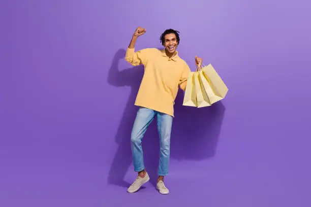 Full size body cadre of shopaholic youth guy fist up hooray open brand store adidas new collection sale isolated on violet color background.