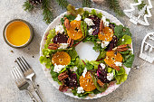 Christmas appetizer. Christmas wreath salad with beetroot, tangerines, feta cheese and pecans on the festive table. View from above.
