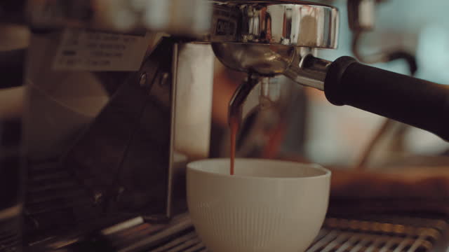 The coffee brewed from the machine is flowing into the cup ready to drink.