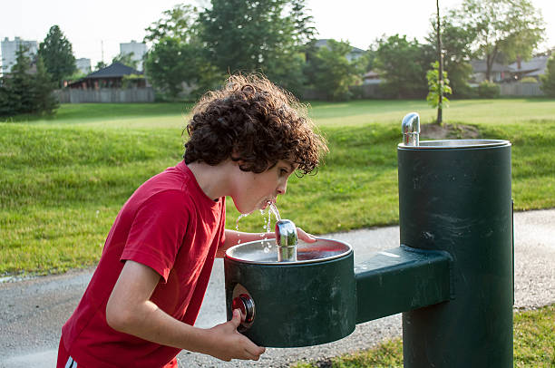 Little girl drinks from a water fountain
