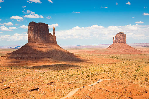 The Monument Valley in UtahArizona state with the crossing road in the desert - The valley is considered sacred by the Navajo Nation - USA - True color photography