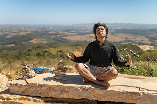 Man meditating on a rock in Minas Gerais, Brazil