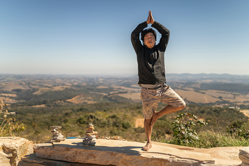 Japanese man balancing with one leg on a rock in Minas Gerais, Brazil