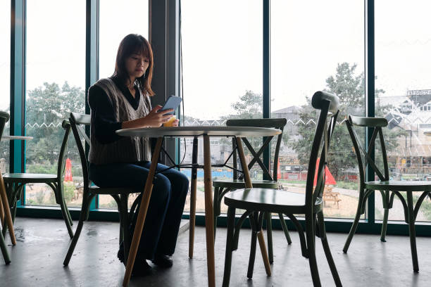 istock Young woman indulges in a refreshing drink while engaging with her smartphone 1733345015