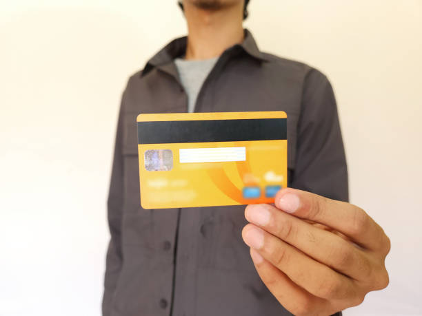 istock Man Holding and showing an orange credit card 1733349454