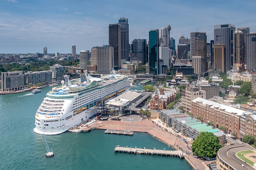 Sydney, NSW, Australia , December 20 2017. An elevated view from the Sydney Harbour Bridge of the Nassau Voyager of the Seas cruise ship at Circular Quay, Sydney, NSW, Australia. The cityscape of Sydney in the background. Voyager Off The Seas is a luxury cruise ship, operated by Royal Caribbean International.