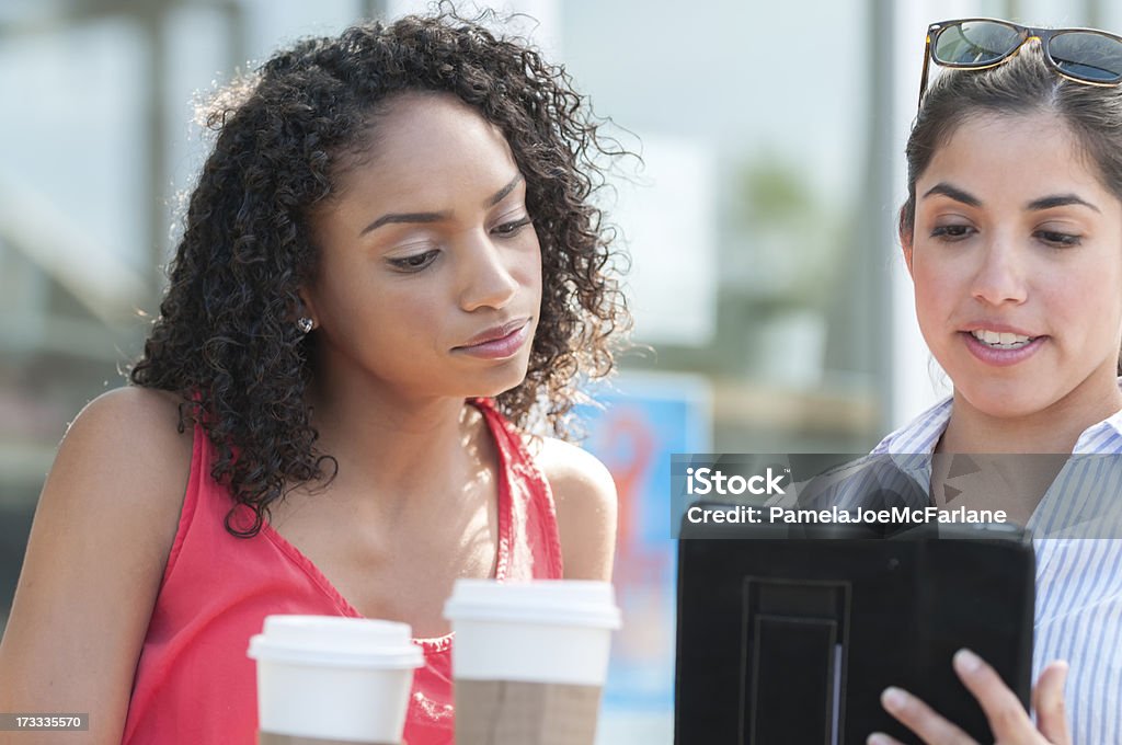 Dos mujeres jóvenes revisión ordenador tableta en un café - Foto de stock de Etnia Latinoamericana libre de derechos