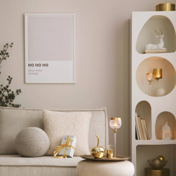 istock Amazing composition on white design shelf with mock up poster frame, christmas decoration, lights, gifts, lanterns ,deer, candles, stars, white corduroy sofa and pouf. Santa claus is coming. Home decor. Template. 1733379897