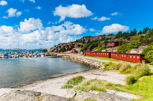 Harbor town's coastal landscape with row of red beach houses and blue sky.