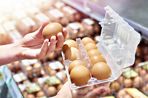 Hands of woman with packing eggs in hand in store