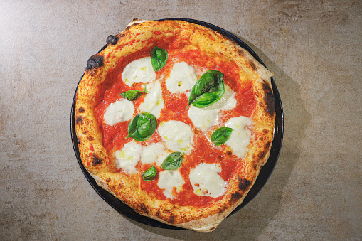 Directly above round pizza Margherita, freshly baked with basil leaves, mozzarella and tomato sauce topping