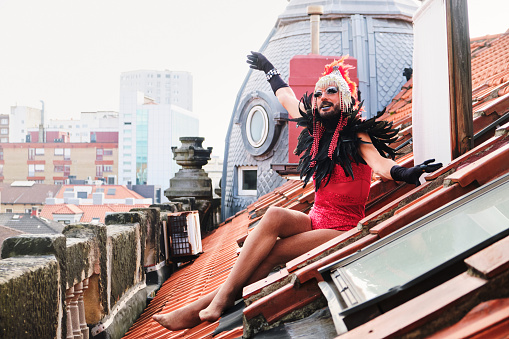Side view photo with copy space of a free drag queen sitting on a roof with city views