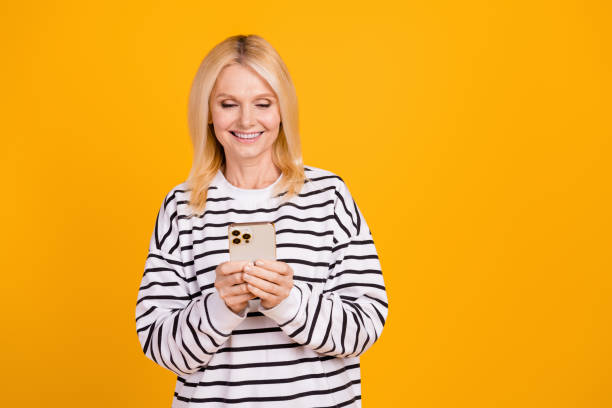 Photo of positive retired lady using gadget browsing apps web typing emails isolated on bright color background
