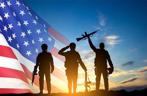 Silhouettes of soldiers with USA flag against the sunset. Greeting card for Veterans Day, Memorial Day, Independence Day