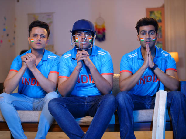 istock Three friends are watching a live cricket match on television - praying for team victory in tense moments 1733454792