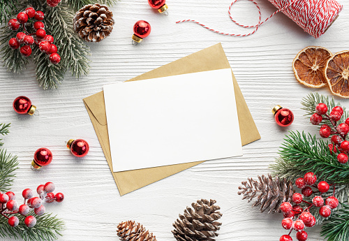 Top view mockup blank paper and envelope . Flat lay of white wooden background,  Christmas decorations and greeting card