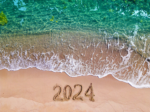 2024 year drawing on sandy beach sea at sunny day