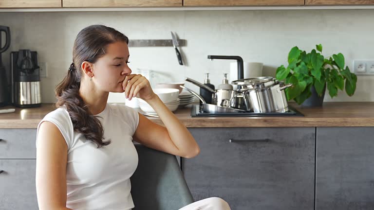 Portrait of a sad tired woman in the kitchen, domestic problems, unstable emotional state