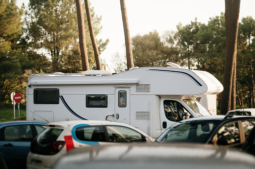 A motor home among cars in a parking lot in a forest area