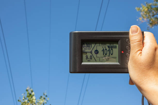Measuring the electric field strength from an electrical transmission line, high-power electrical transmission. Device in hand against the sky