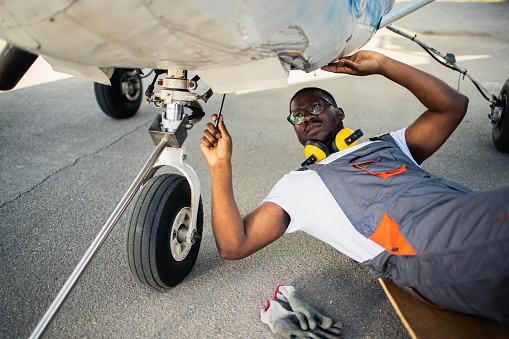 Aircraft mechanic inspecting and checking the function of a jet plane at the airport