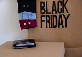 Black friday shopping bag with wallet in front of it on white background and shirts sleeve