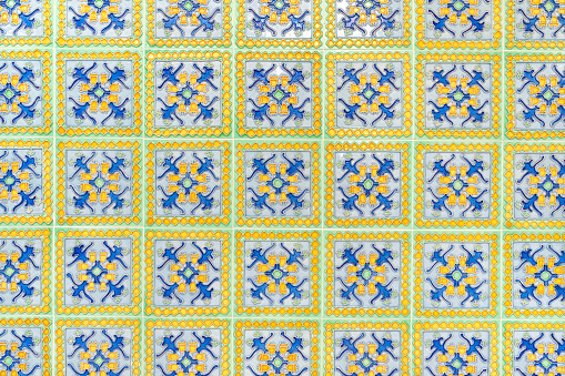Detail of antique wall tiles with geometric shapes and vibrant colors on an old facade