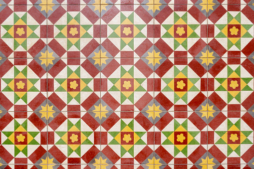 Detail of wall tiles with geometric shapes and vibrant colors on an old facade