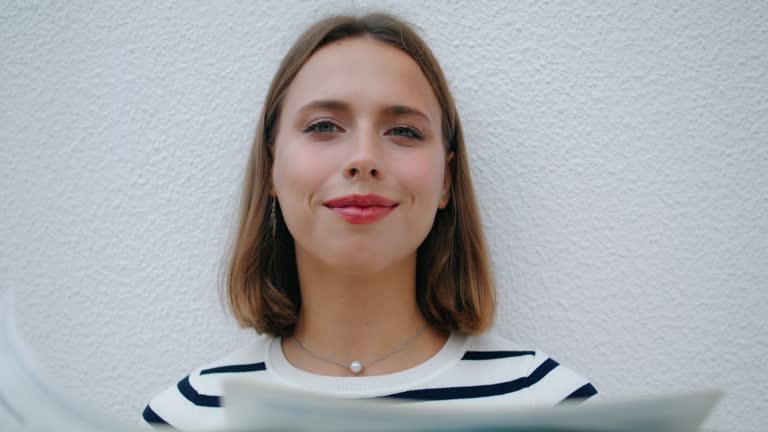 Relaxed girl reading newspaper in morning closeup. Smiling woman looking camera