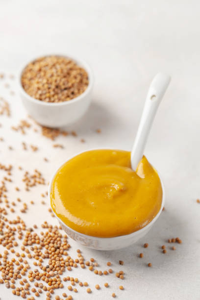 istock Mustard sauce in a bowl and seeds on a bright background. 1733699907