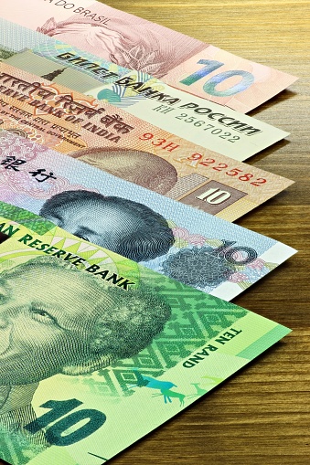 banknotes of the BRICS states on wooden background