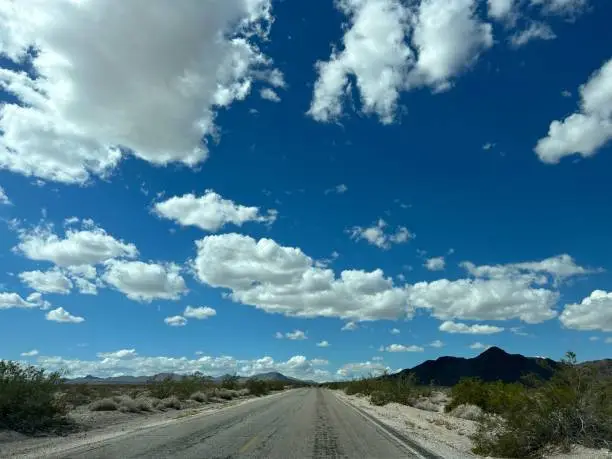 Lonely desert highway in the middle of the day with a spotted sky