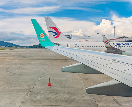 Chiang mai - Thailand. October 7, 2023: Nok Air and China Eastern airplanes under a beautiful blue sky with clouds at Chiang Mai International Airport. Travel concept