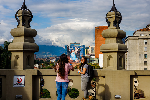 Medellin, Colombia - January 10, 2023: Mural by Fernando Botero with two young people photographing themselves in the foreground
