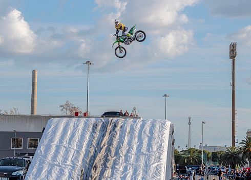 Bari, Italy - April 2023: professional rider at the FMX (Freestyle Motocross) make an acrobatic jump at the motorshow inside the spaces of the Bari trade fair