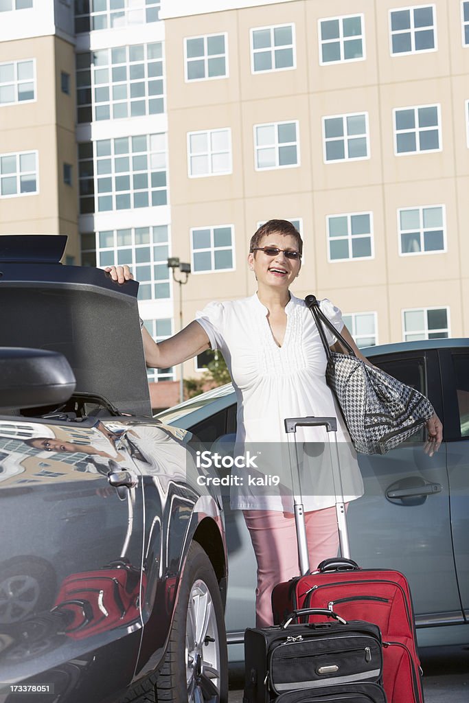 Dojrzała kobieta Umieszczenie bagażu w samochodzie - Zbiór zdjęć royalty-free (50-54 lata)