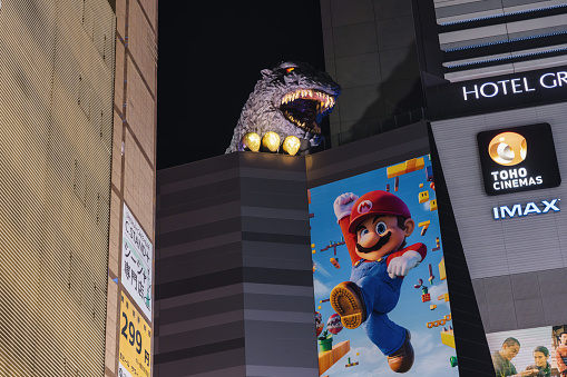 Tokyo, Japan - April 09, 2023: Godzilla sculpture on a building of the Toho Cinemas in Kabukicho, Shinjuku, Tokyo, at night. Kabukicho is an entertainment district in Shinjuku. The famous Kabukicho area has many movie theaters