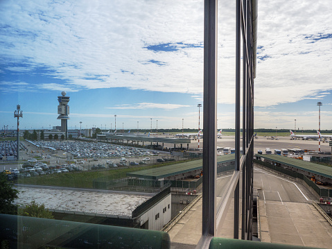 Milano, Italy - 8 august 2023: Car Parking and Airport Control Tower reflected on office windows, Milan Malpensa Airport -Italy.