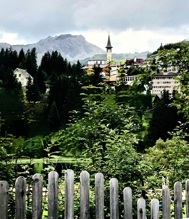 A small village in Switzerland highlighting a church, rolling hillsides and mountain ranges