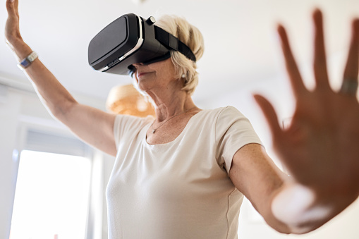 Happy senior woman with virtual reality in living room