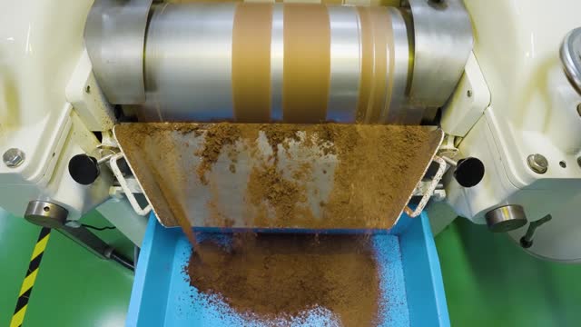 Close-up slow motion of chocolate refining process with roll cylinder machine, Malaysia