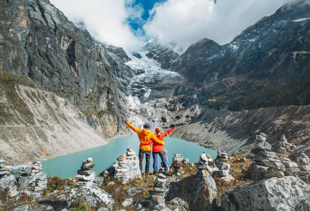 istock Couple trekkers dressed bright jackets on the rock enjoying a glacier falling in high altitude Sabai Tso glacial lake cca 4350m. Makalu Barun National Park, Mera peak climbing route, Nepal. 1733851647