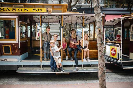 A large Caucasian family sit on the Hyde street cable car for a photo in downtown San Francisco Bay area, California, USA.